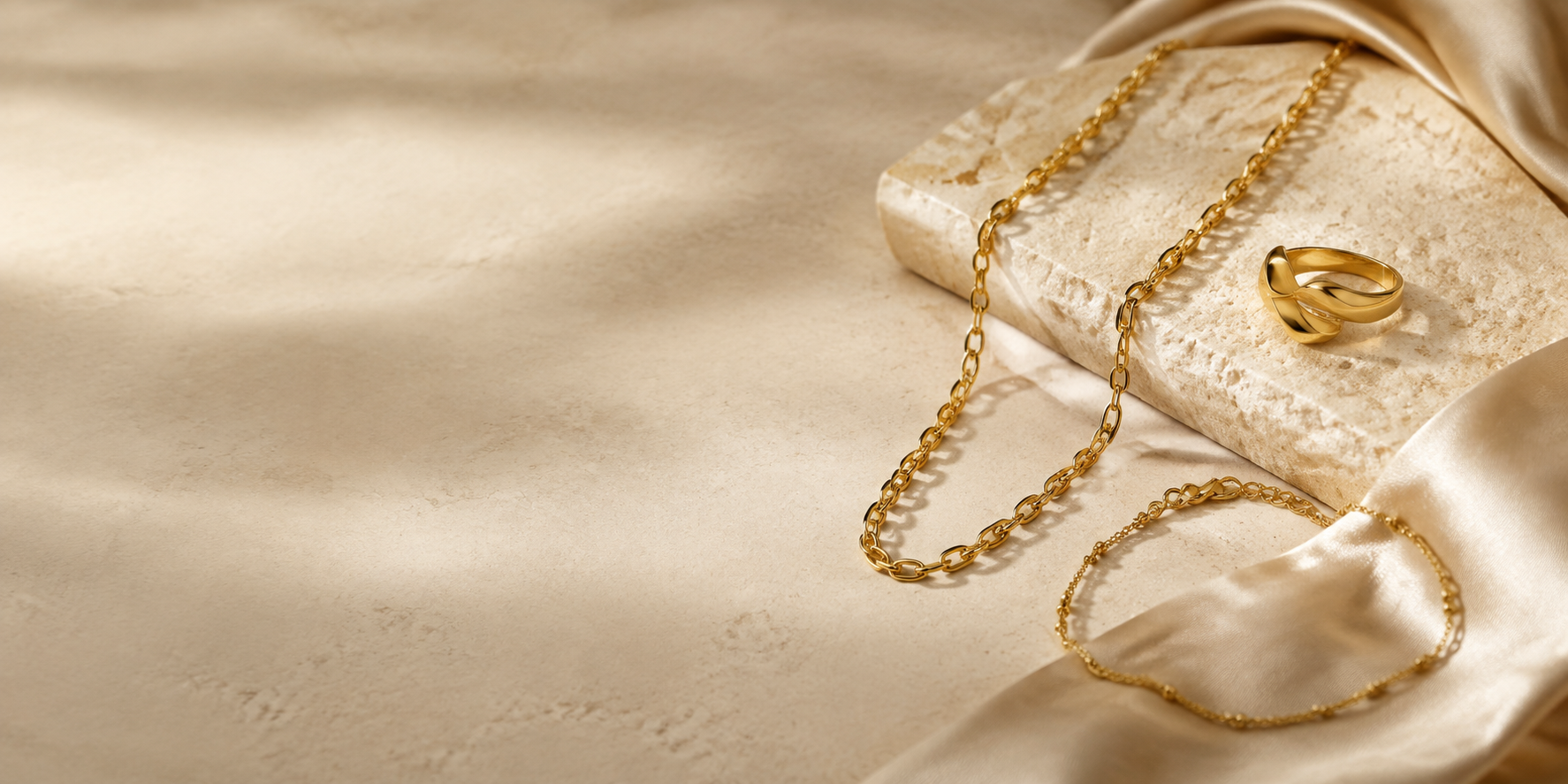 Solid gold jewelry on warm beige stone and silk